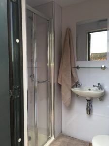 View of shower with sliding door, white sink and mirror