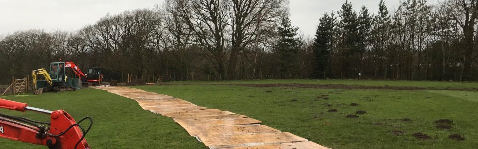 ground protection boards across a field with diggers in distance