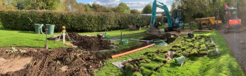 sewage treatment plant installation with a digger and dumper in garden and tank in the ground